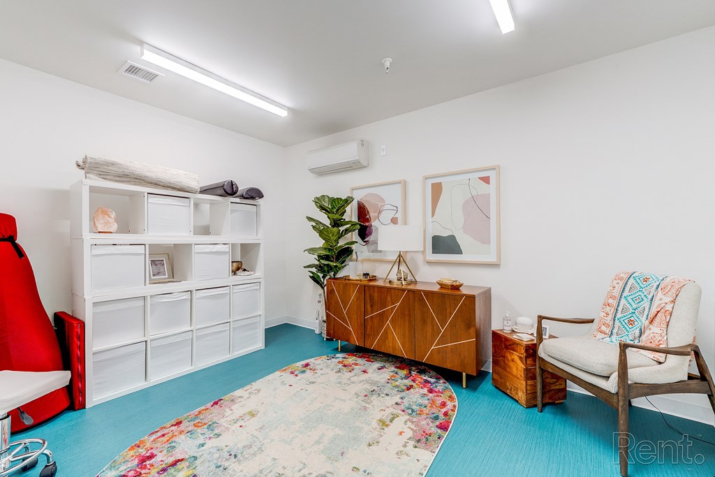 a living room with a blue carpet and a white cabinet and a chair