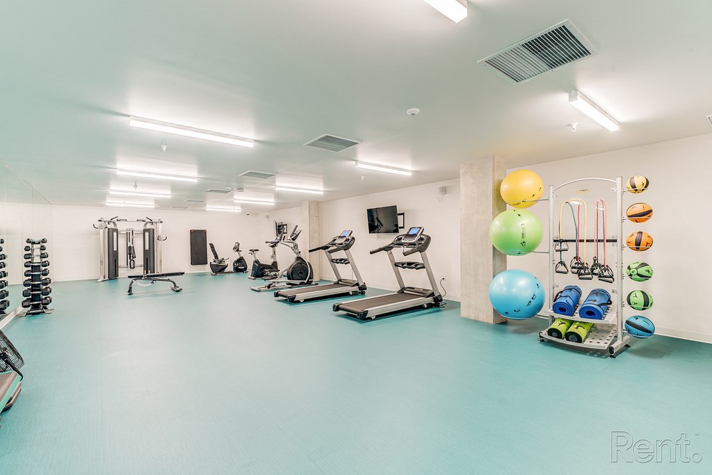 a gym with cardio machines and weights and balloons on the wall