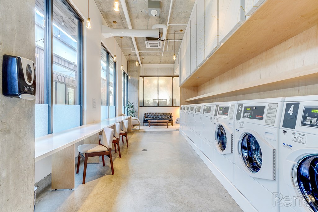 a laundry room with washers and dryers and a row of chairs