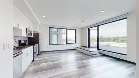 A modern kitchen with white cabinets and a large window overlooking the landscape.