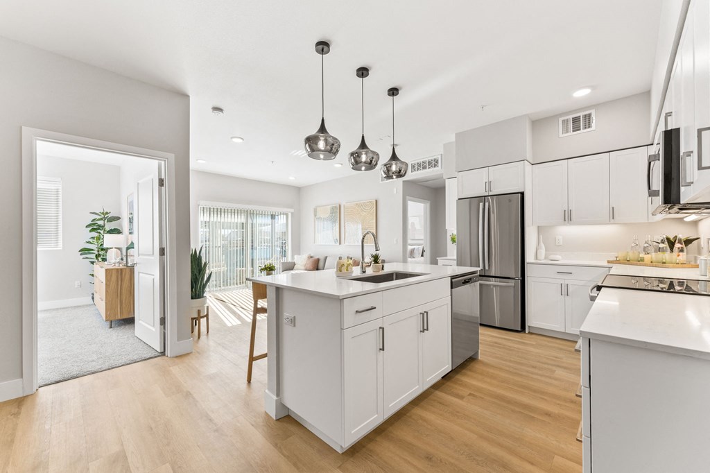 an open kitchen and dining room with white cabinets and stainless steel appliances