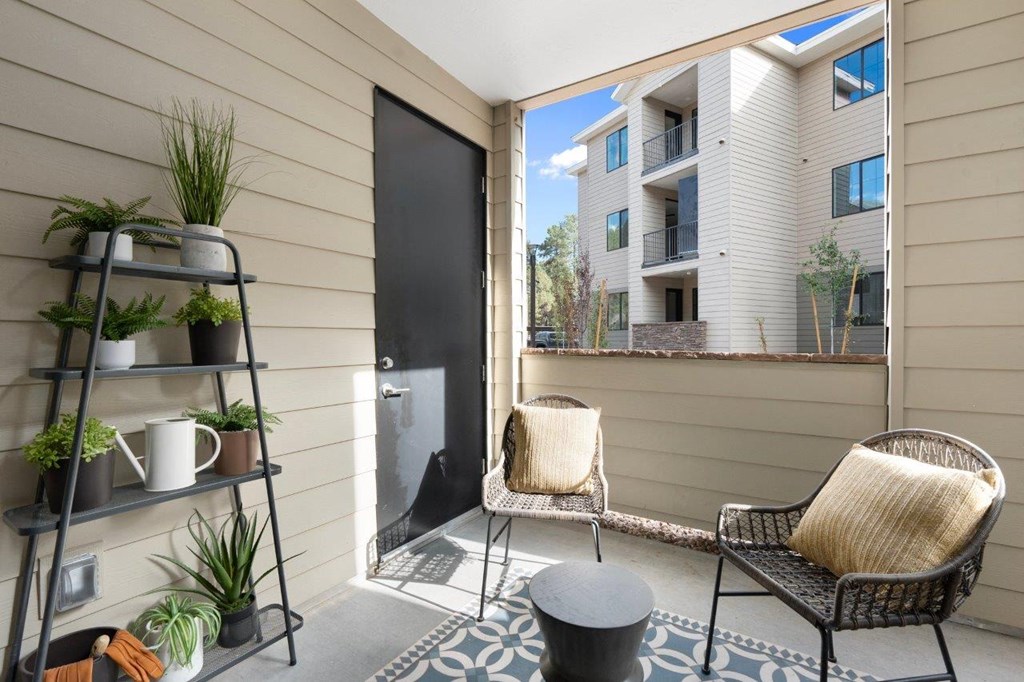 a small porch with two chairs and a door to a building