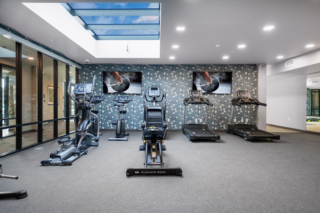 A gym with a variety of equipment including treadmills, stationary bikes, and elliptical machines.