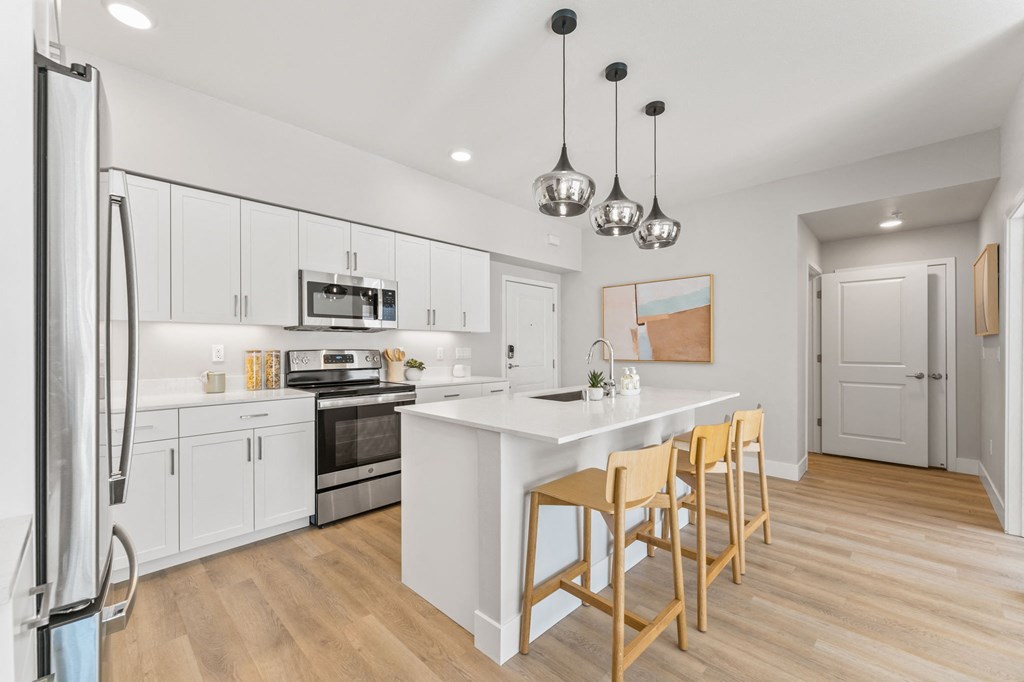 a kitchen with white cabinets and a white island with chairs