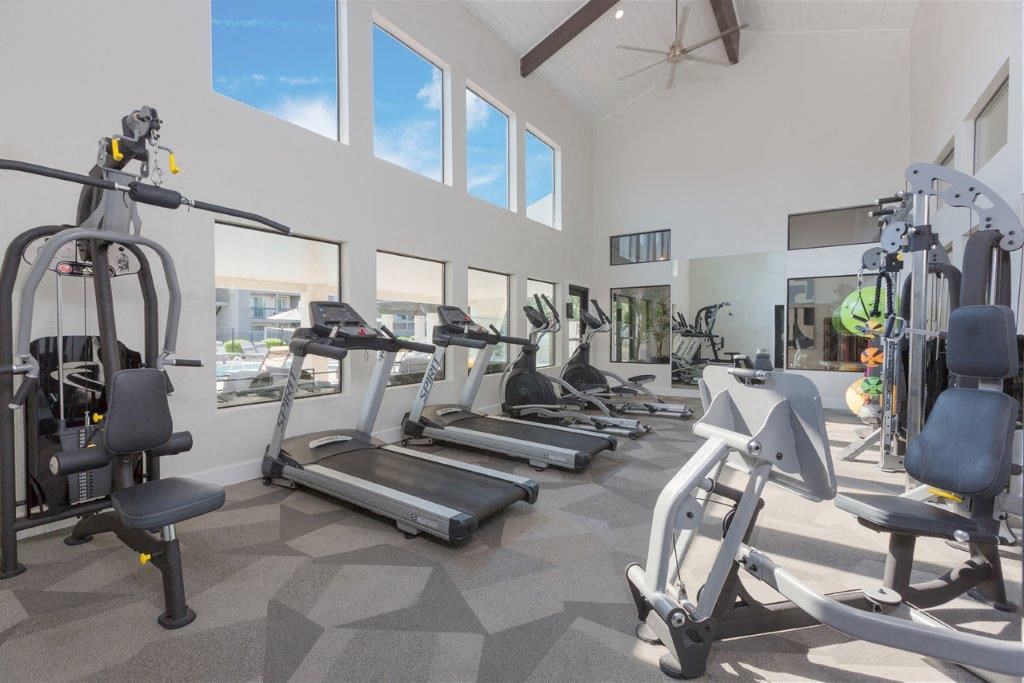 a gym with cardio equipment and windows in a building