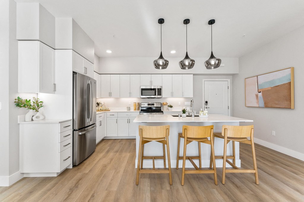 a kitchen with white cabinets and a large island with three stools