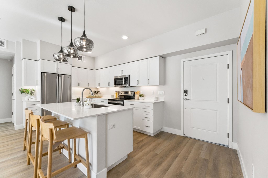 a kitchen with white cabinets and a large island with chairs