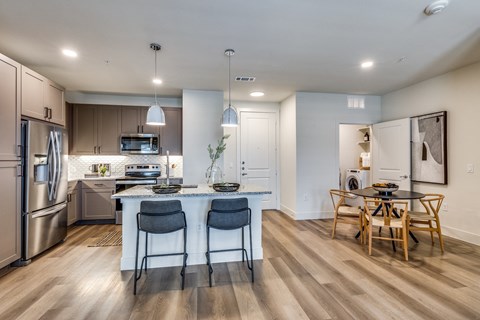 an open kitchen and dining room with a large island with blue chairs
