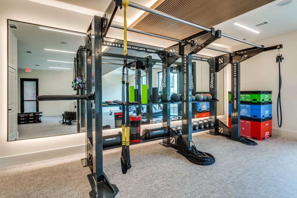 a gym with weights and other gym equipment in a room with a large mirror