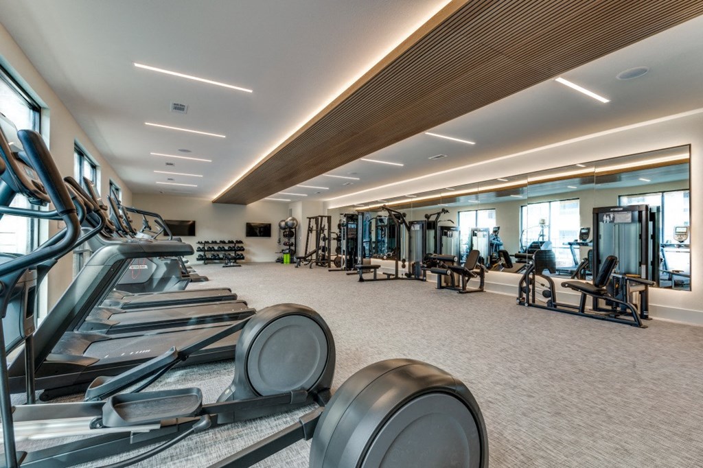 a gym with cardio equipment on the floor and glass walls
