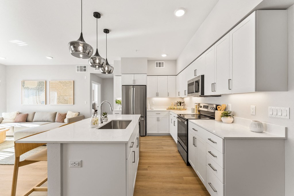 an open kitchen and living room with white cabinets and a white counter top