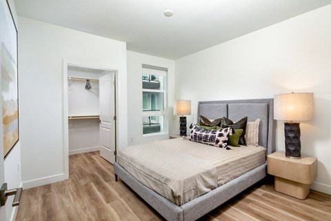 A bedroom with a large bed and a nightstand with a lamp.