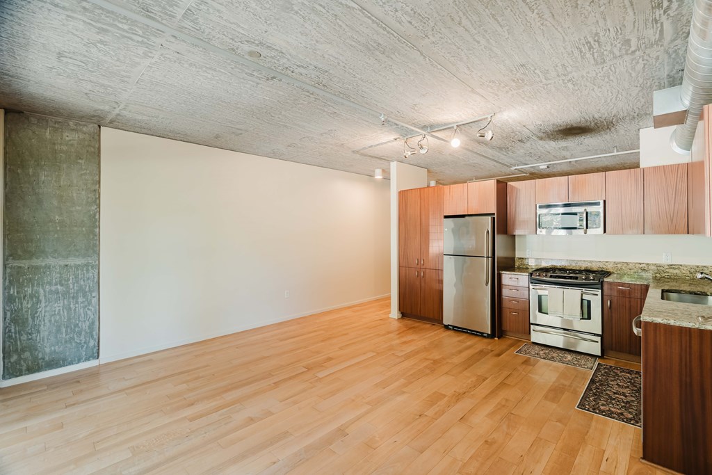 A kitchen with wooden floors and a stainless steel refrigerator.