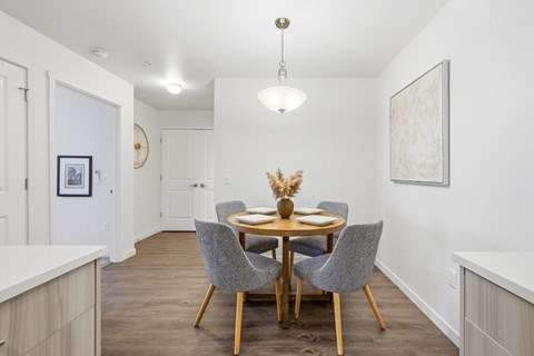 A dining room with a round table and grey chairs.