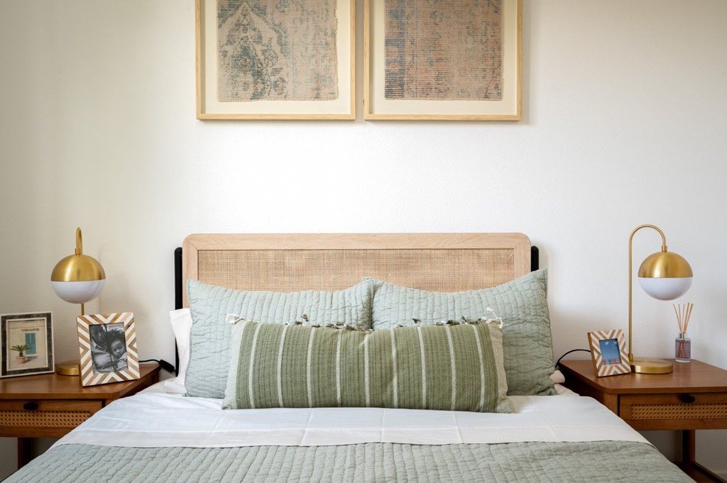 The Wes Gresham Oregon Apartments bedroom with A bed with green striped pillows and a wooden headboard.