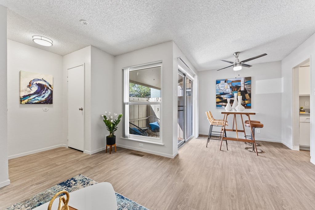 A room with a ceiling fan and a dining table with chairs.