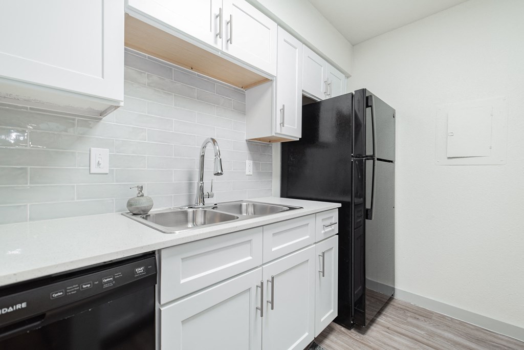 a kitchen with white cabinets and a black refrigerator