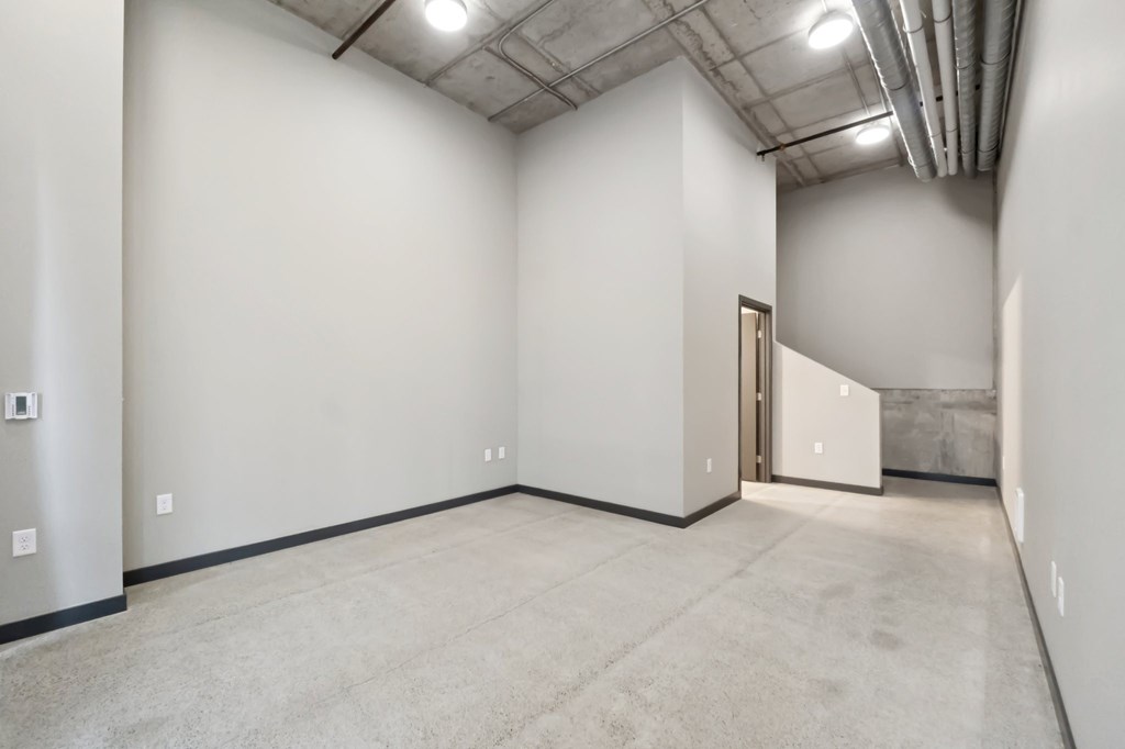A large, empty room with a carpeted floor and a door on the right side.