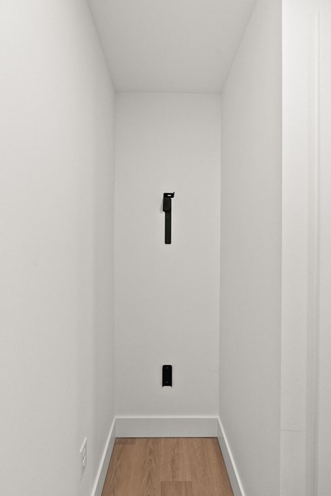 A white hallway with a black door.