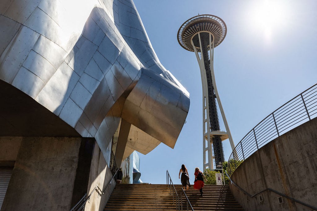 people walking up a set of stairs next to the space needle