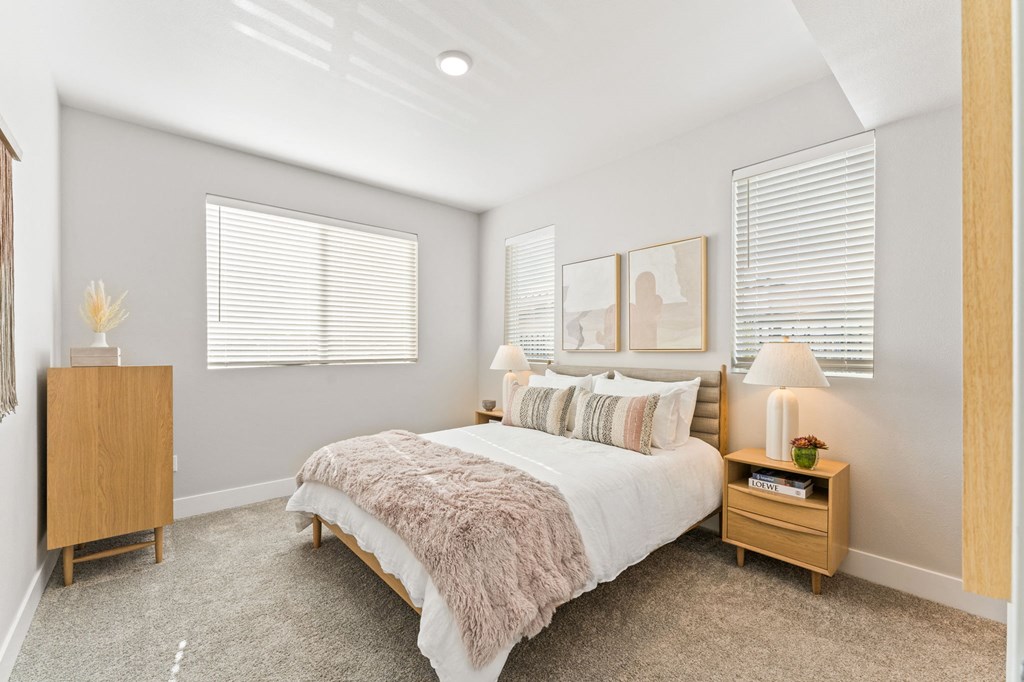 a bedroom with a bed and two windows