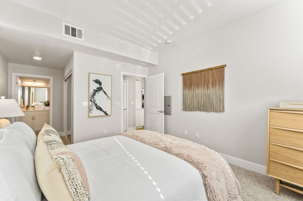 a bedroom with a bed and a dresser and a bathroom