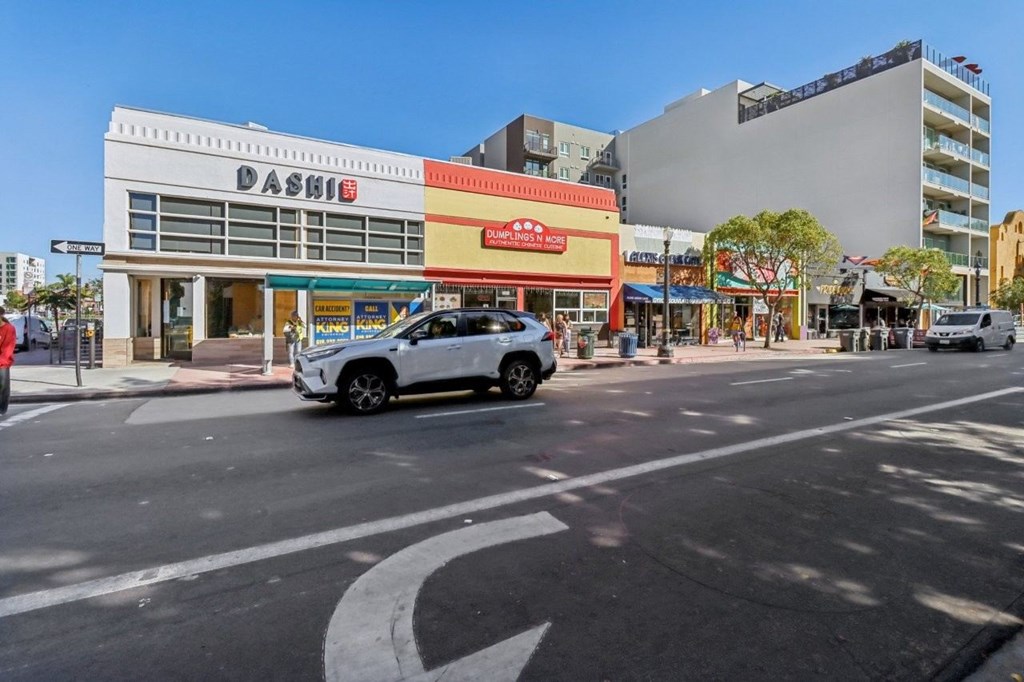 A white car is parked on the street in front of a Dashie store.