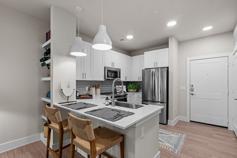 an open kitchen with a large island with a counter top and chairs