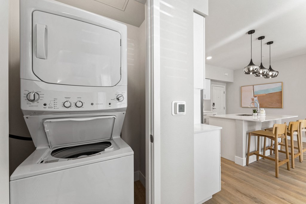 a white washer and dryer in a kitchen with a dining table and chairs