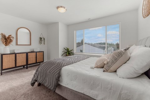 A bedroom with a large bed and a window with blinds.