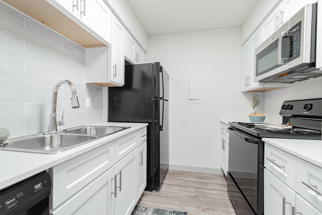 a kitchen with white cabinets and a black refrigerator