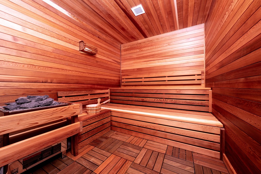 A wooden sauna with benches and a light on the ceiling.