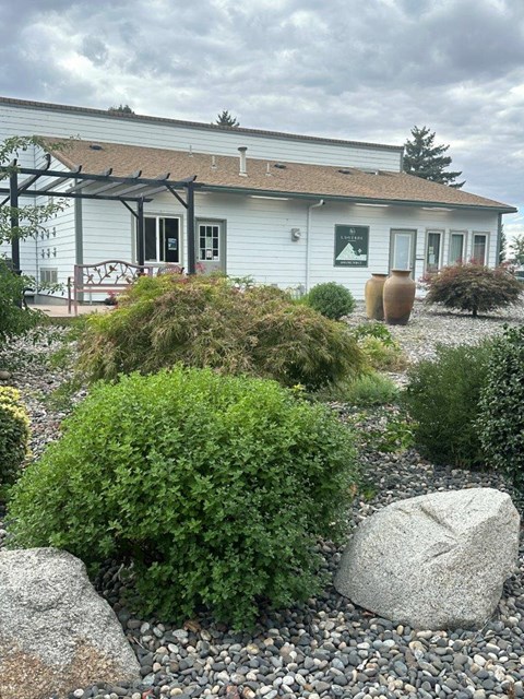 A white house with a grey roof and a gravel garden in front.