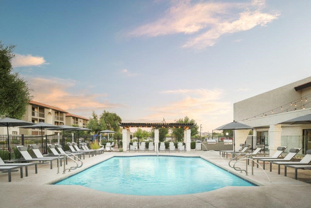 a swimming pool at a hotel with chairs and umbrellas