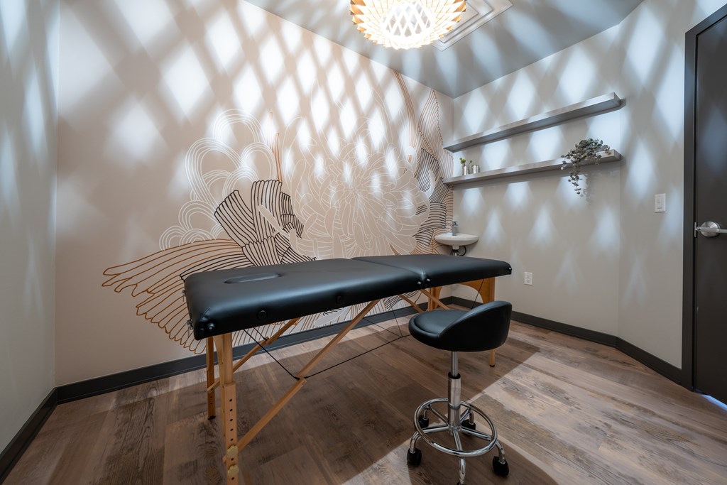 A massage table in a room with a wooden floor and a patterned wall.