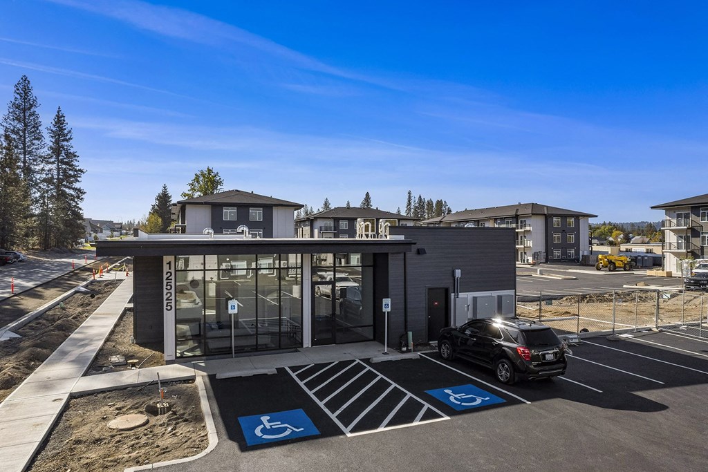 A parking lot with a building and a car in front of it.