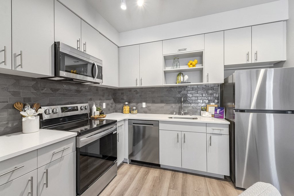 A modern kitchen with white cabinets and stainless steel appliances.