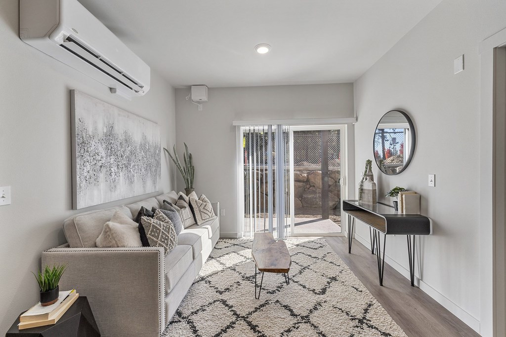 A living room with a grey couch, a black and white rug, and a painting on the wall.