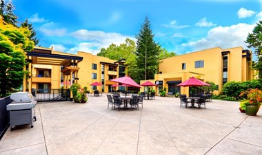 12 Central Square outdoor patio with tables, greenery and red umbrellas