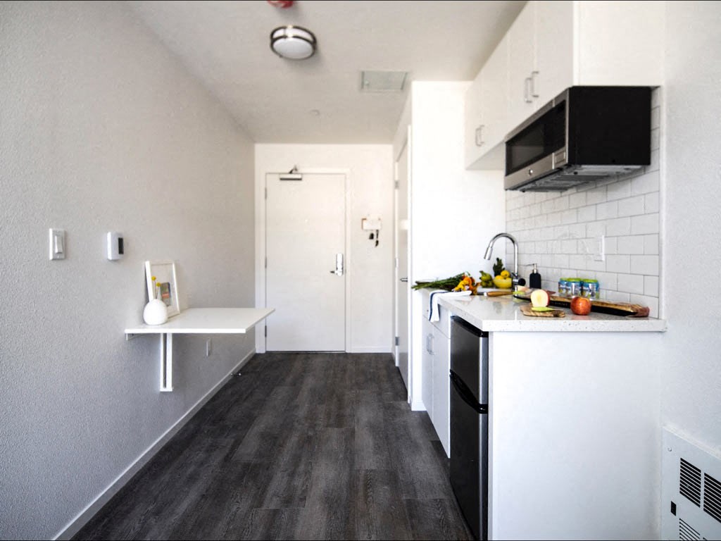 a small kitchen with white cabinets and black appliances