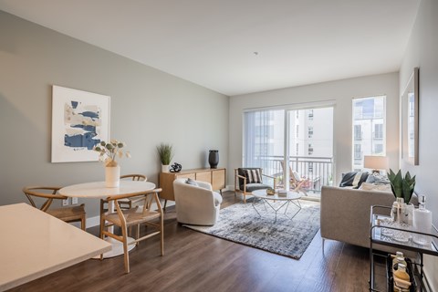 A living room with a white table and chairs, a couch, a rug, and a painting on the wall.