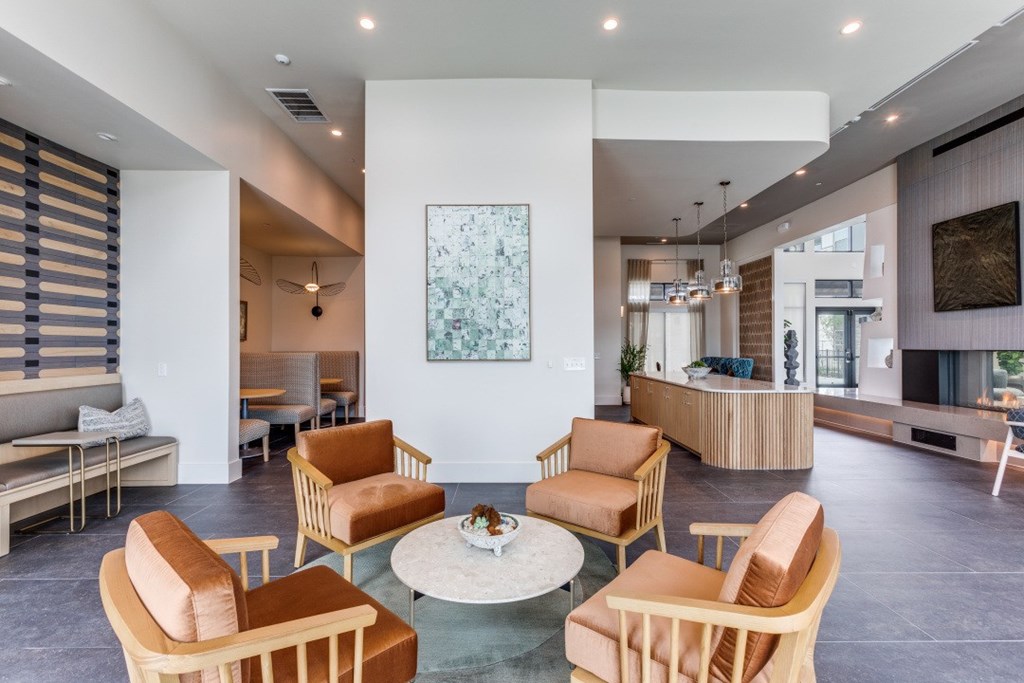 A living room with a white coffee table surrounded by orange chairs.
