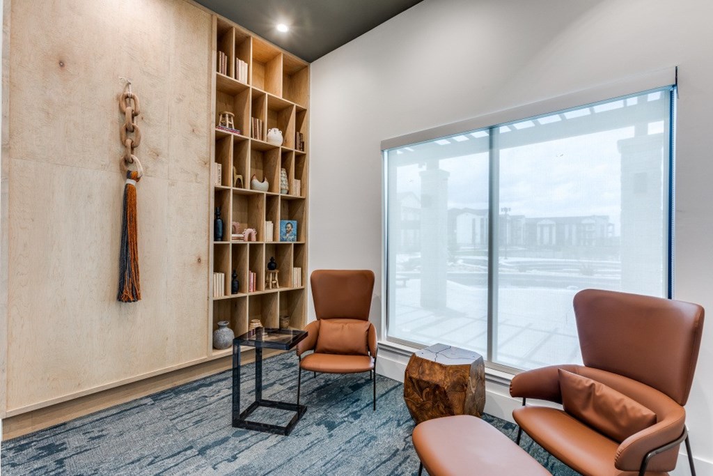 A room with a chair, a table and a bookshelf.