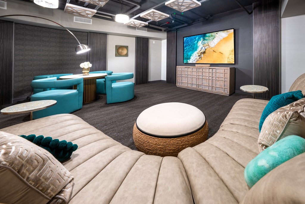 A modern living room with a large screen TV and comfortable seating.