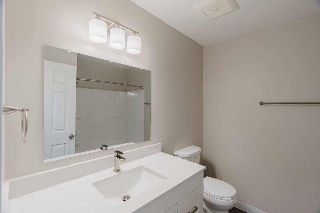 A white bathroom with a toilet, sink, and mirror.