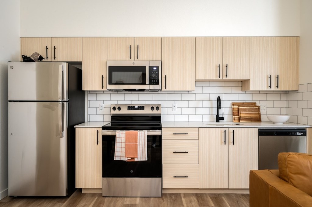 The Wes Gresham Oregon Apartments  A modern kitchen with wooden cabinets and a stainless steel refrigerator.