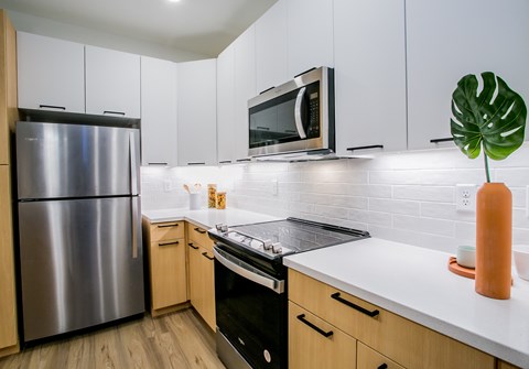 A modern kitchen with a stainless steel refrigerator and wooden cabinets.
