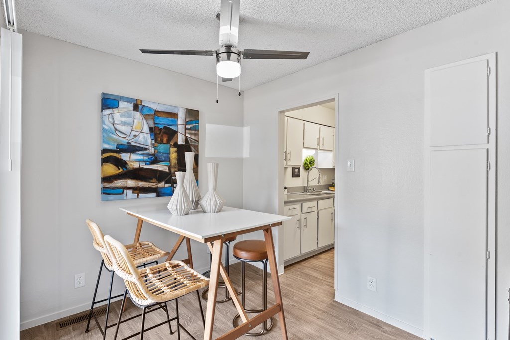 A dining room with a table and chairs and a painting on the wall.