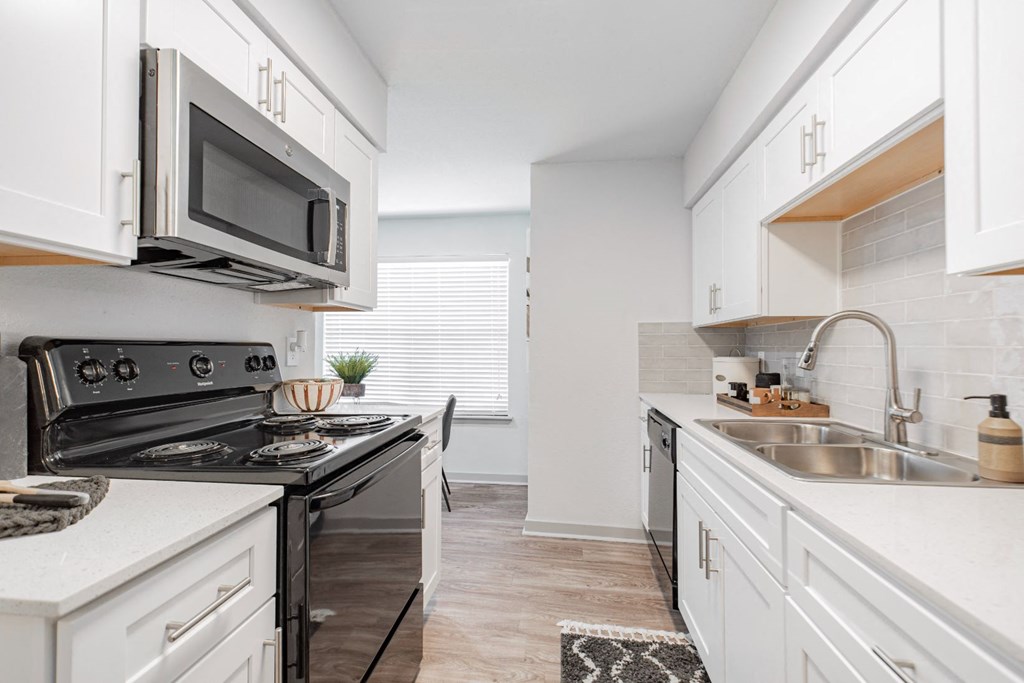a kitchen with white cabinets and a stove and a microwave