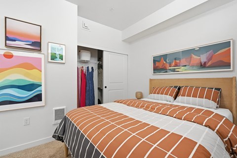 A bedroom with a large bed and two paintings on the wall.